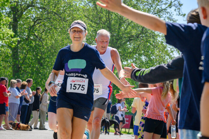 A participant in a charity race, wearing a Response t-shirt and high-fiving spectators along the route.