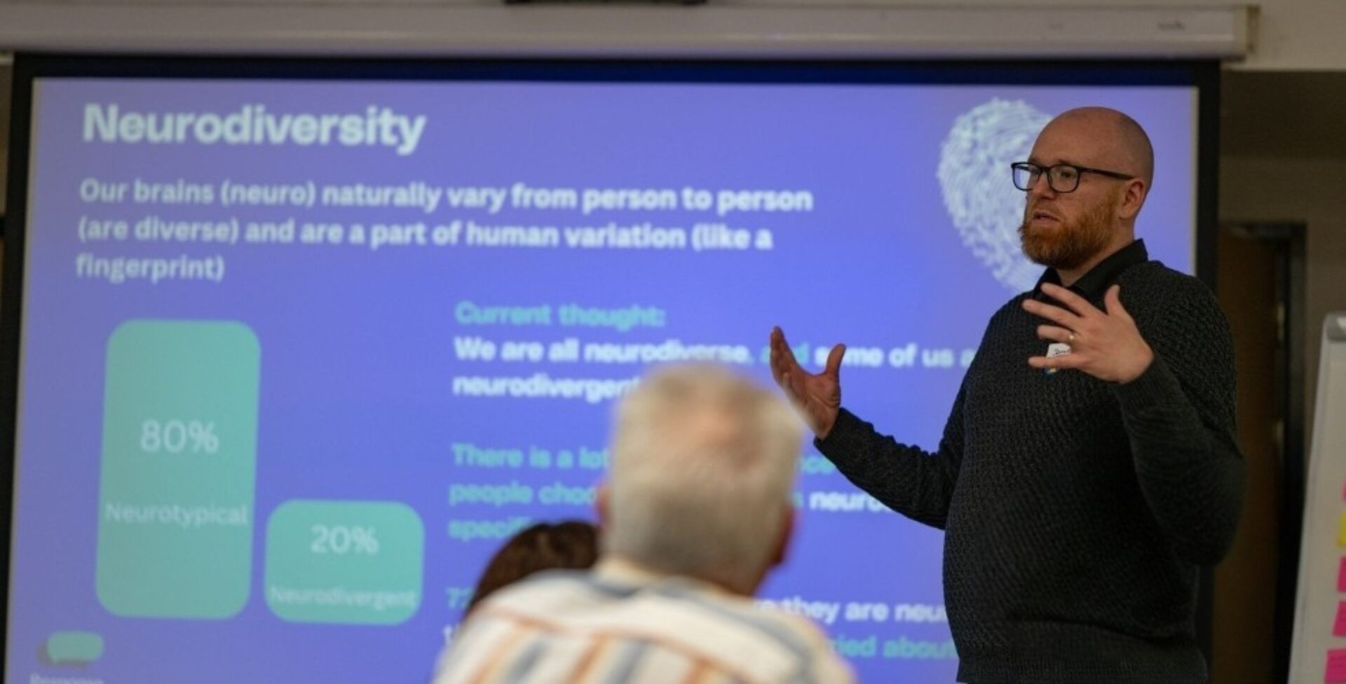 Jamie Douglas from Response standing in front of presentation slides delivering his neurodiversity training.