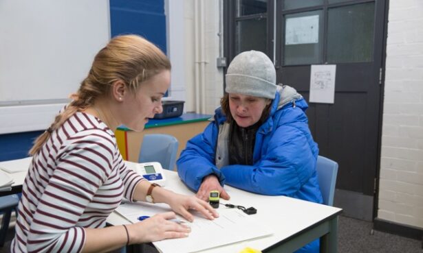 Two women sat at a table together having a conversation, looking at paperwork.