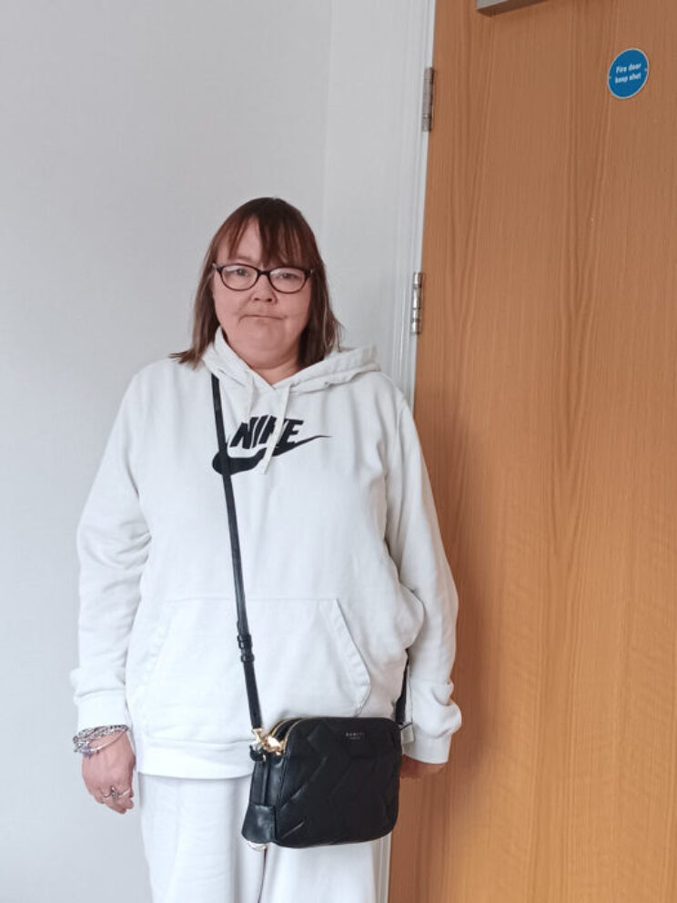 Woman with glasses in a white hoodie smiling.