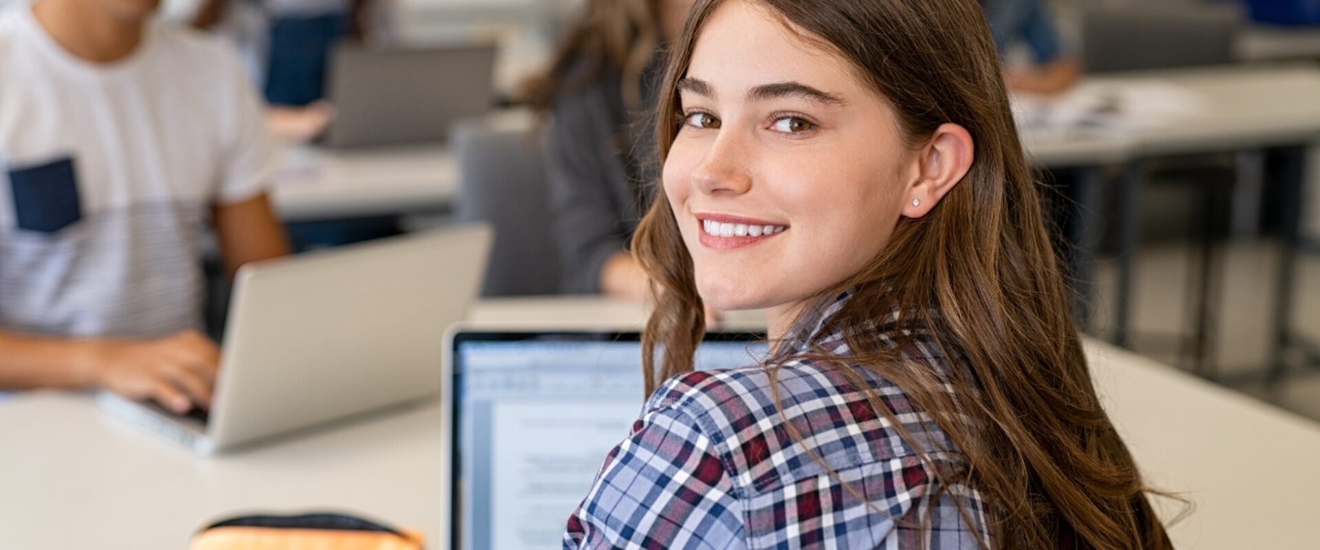 Young girl using laptop in classroom.