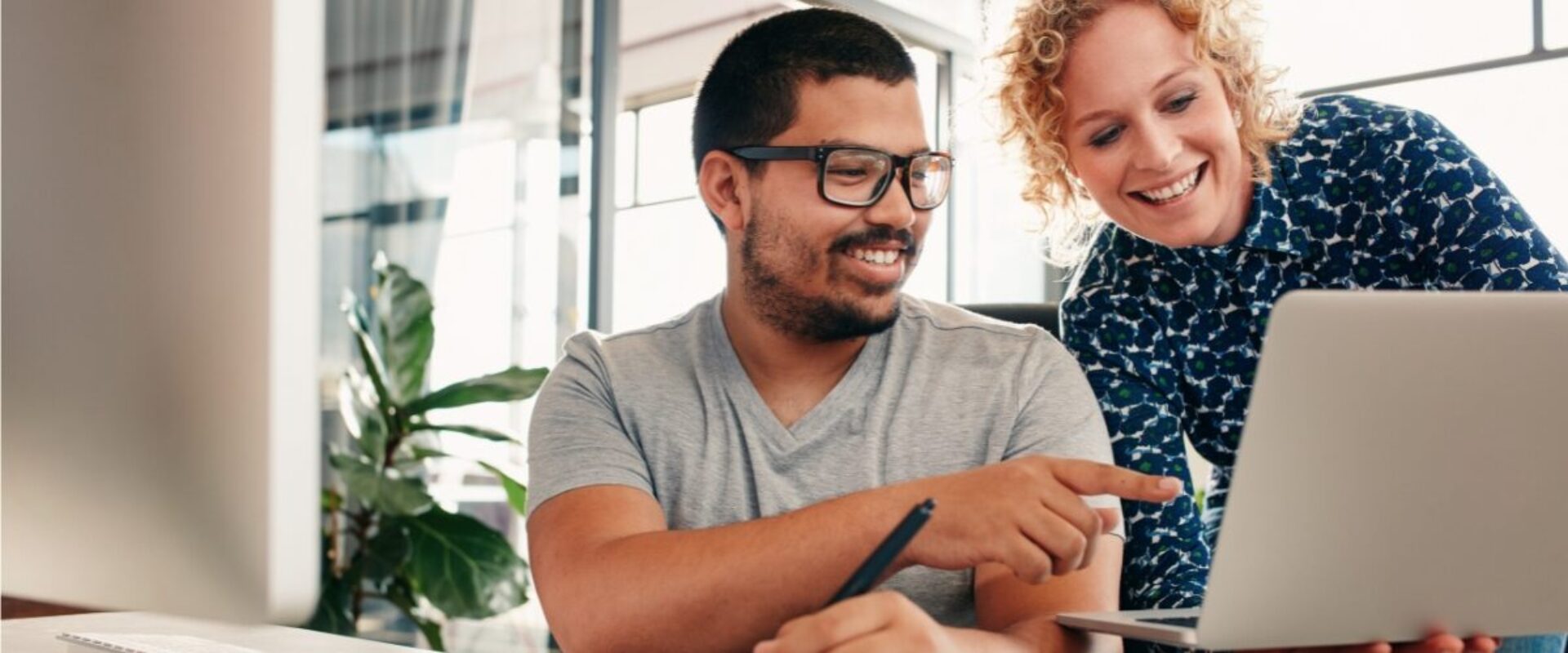 Two people looking at a laptop and smiling.