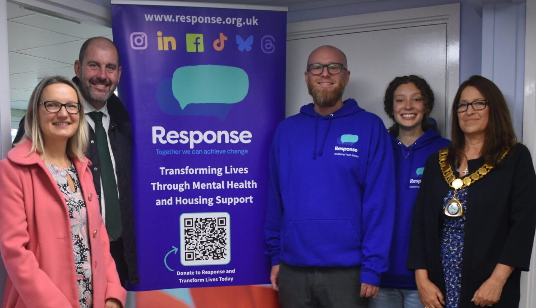 Five people, including a mayor, standing beside a Response charity banner for mental health and housing support.