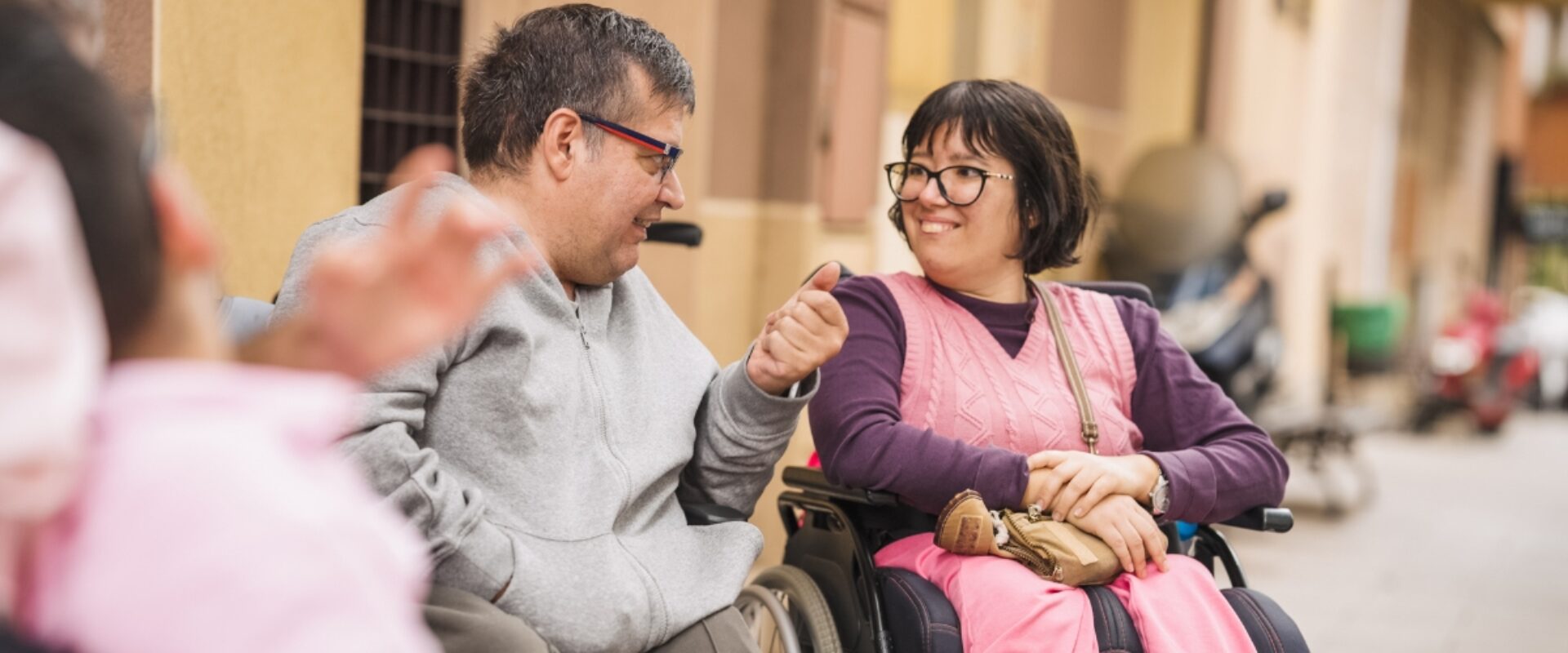 Two people smiling at each other outdoors.