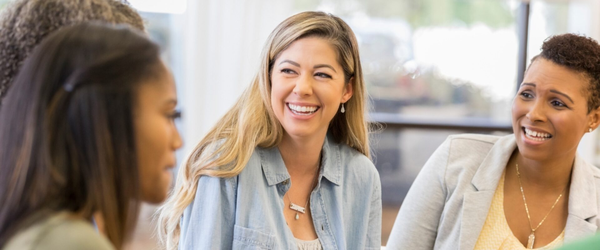 Women sat in a group of four, conversing and smiling.