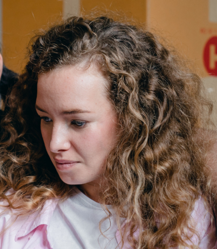 Woman with brown curly hair looking at a mobile phone.