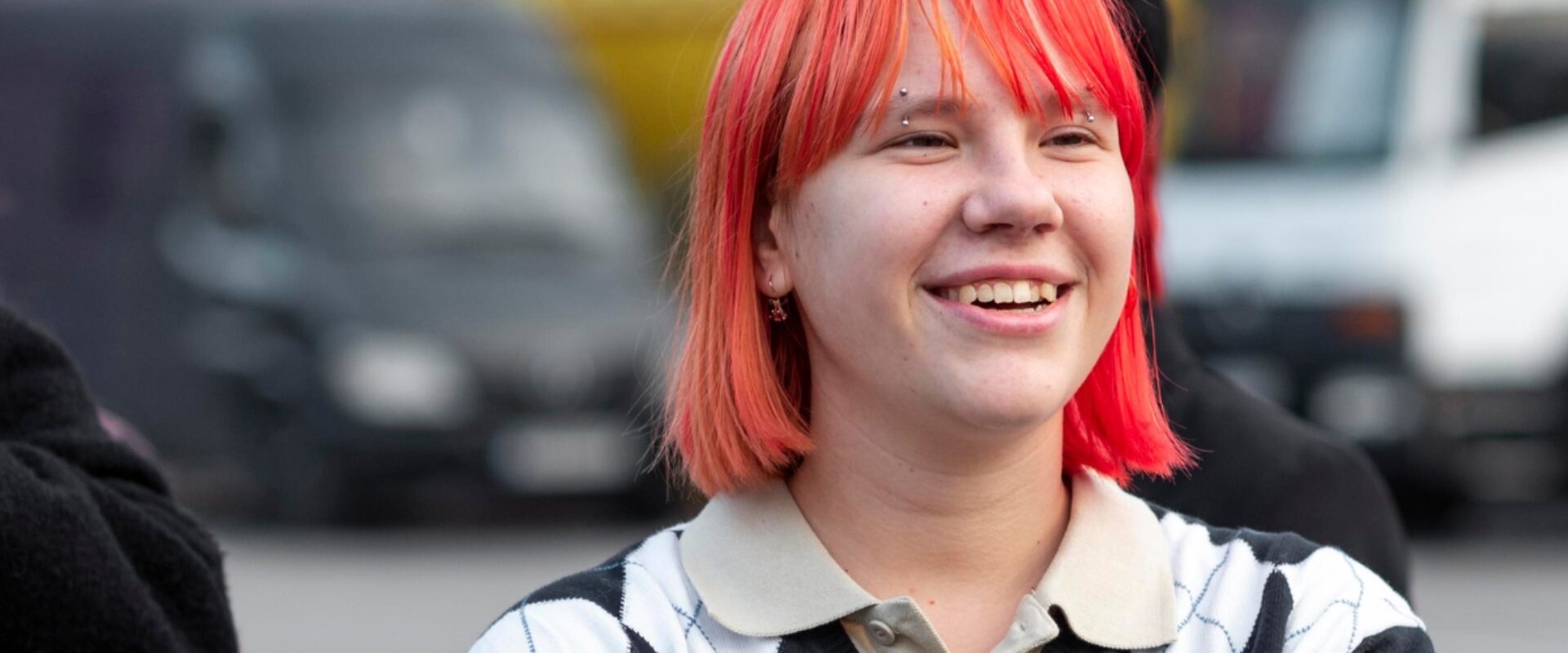 Young girl with red hair smiling outdoors.