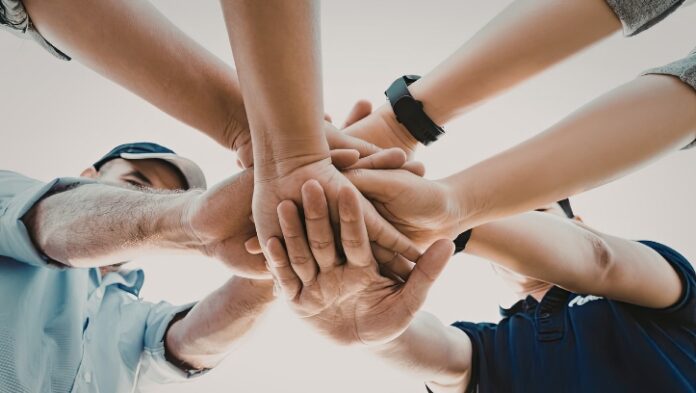 A group of people placing their hands together, symbolising teamwork.