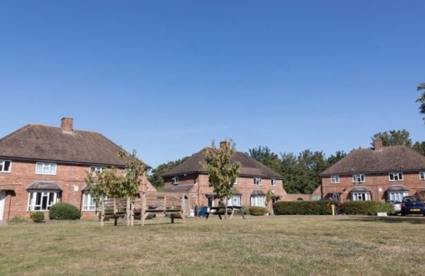 A street of red-brick houses with blue sky.