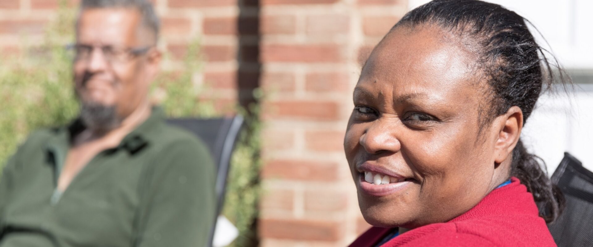 Woman in red jumper, smiling towards the camera.
