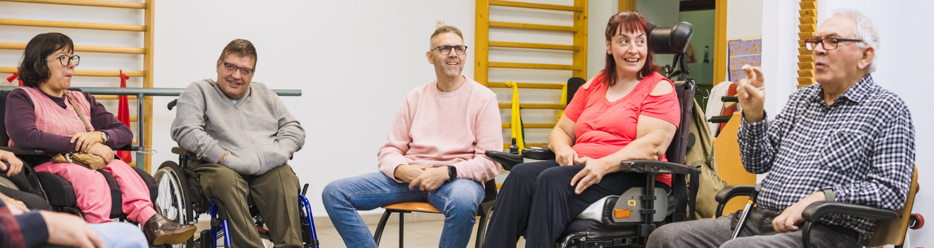 A group of people in a hall chatting, including wheelchair users.