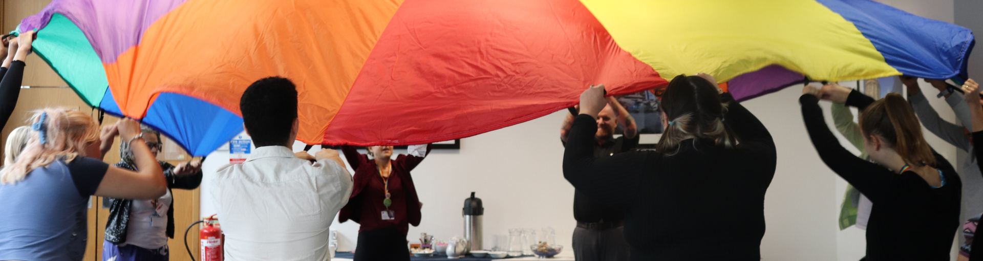 Response colleagues waving a rainbow coloured parachute at a team training day.