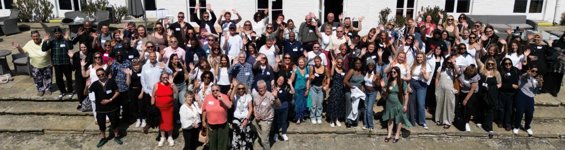 A group shot of a large group of Response staff at a team training day, waving at the camera.