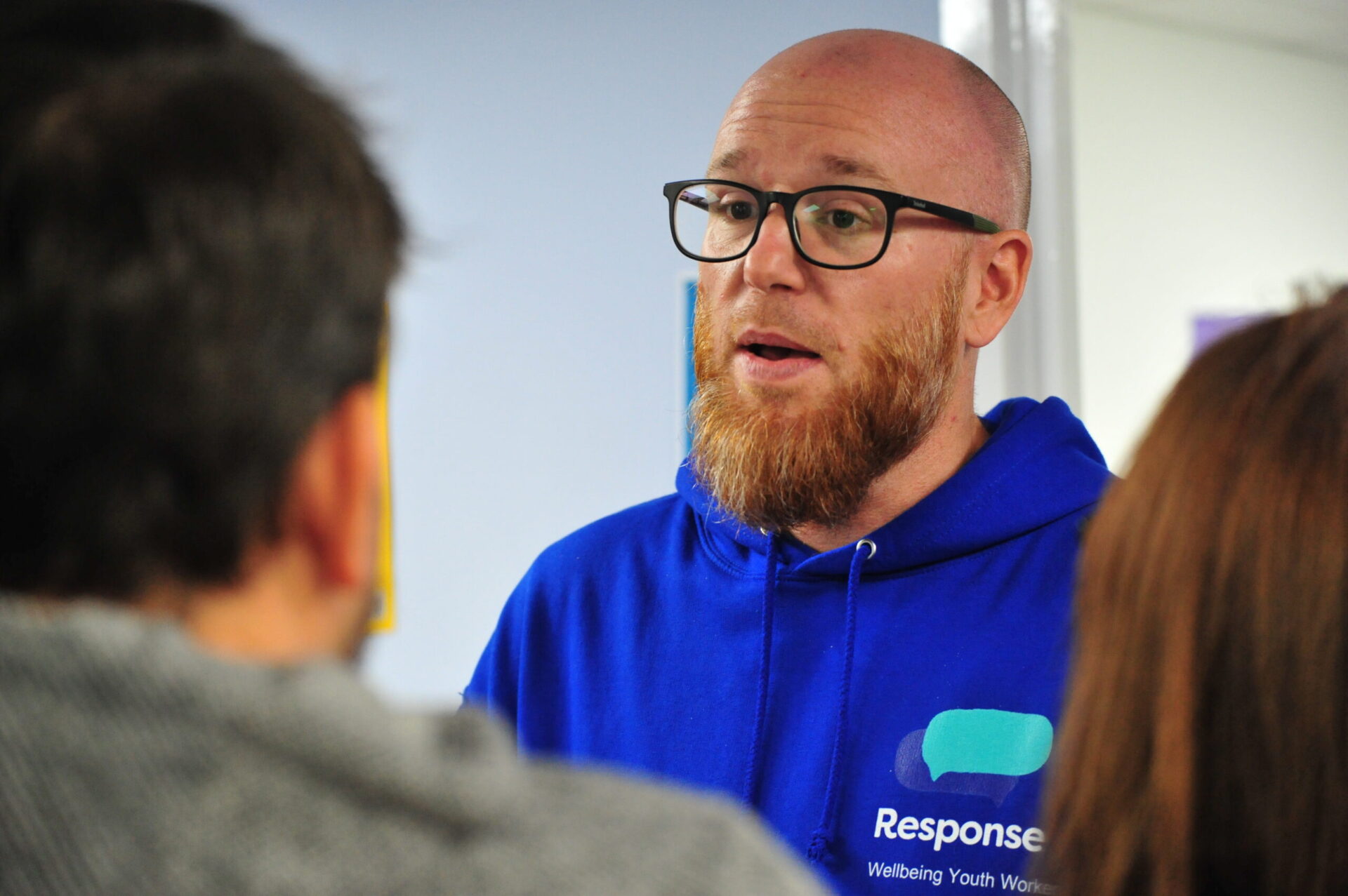 Associate Director of Response Youth, Jamie Douglas, wearing a blue Response hoody and talking to a group of people at the Thatcham Wellbeing Hub.