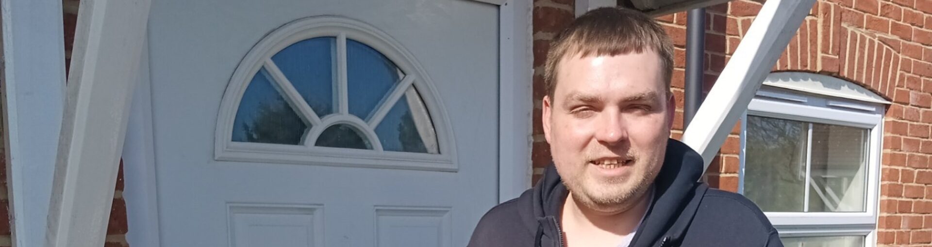 Response resident, Scott, in black hoodie stood in front of white door.