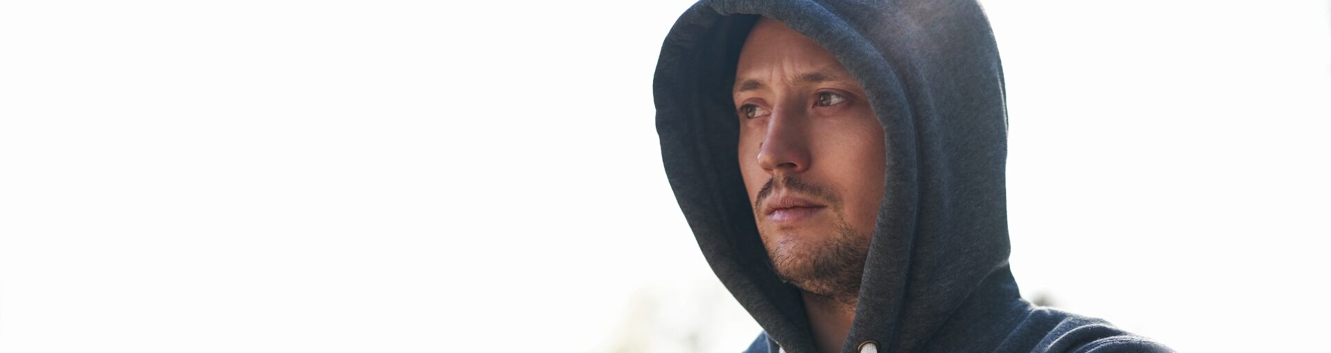 Man in grey hoodie, stood outdoors.