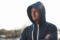 Man in grey hoodie stood outdoors.