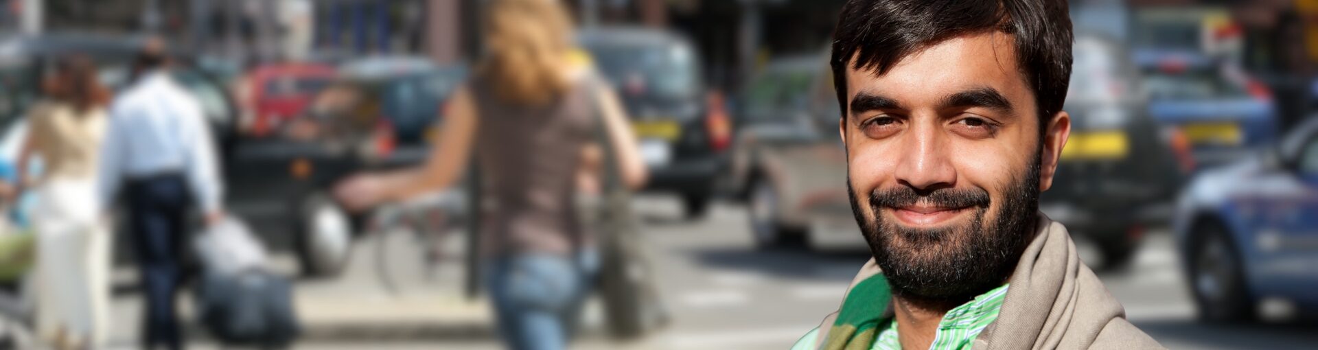 Man stood on busy street, with background blurred.