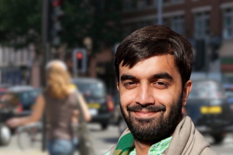Man stood on busy street, with background blurred.