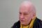 Photo of man in black coat and yellow scarf.